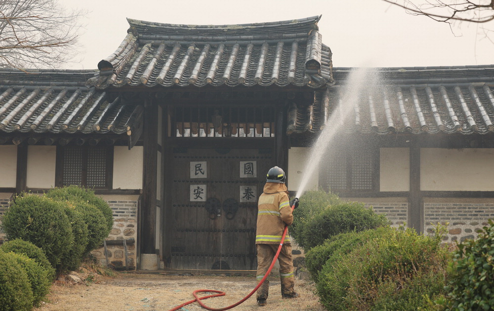 26일 안동 하회마을에서 소방관이 불씨가 옮겨붙지 않도록 물을 뿌리고 있다. 연합뉴스